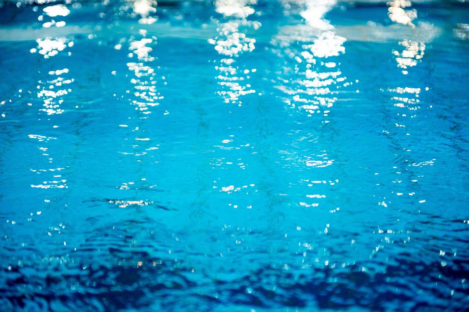 Wasseroberfläche mit Lichtreflexionen in verschiedenen Blau- und Türkistönen. Sanfte Wellenbewegungen sichtbar.